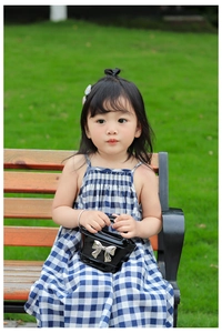 Detail of laser finish mini handbag with silver bow on a blue gingham dress