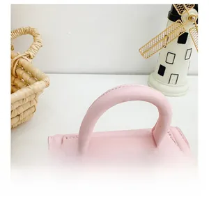 Detail of pink PU leather children's handbag featuring smooth handle and letter branding