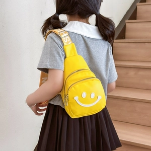 Kids bright yellow chest bag with smiley face patch and lettered strap outdoors