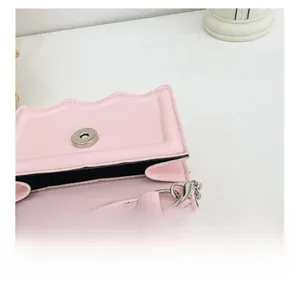 Detail of pink shoulder bag showing wave edge, magnetic buckle and detachable silver hook