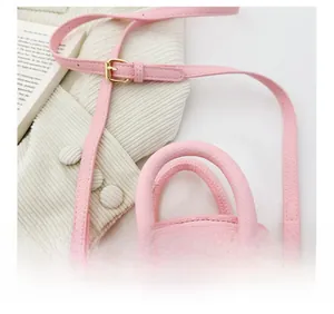 Dettaglio della borsa in pelle rosa con chiusura dorata e manico cilindrico elegante