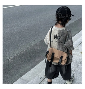 Outdoor back view of child's two-tone street style t-shirt with brown messenger bag