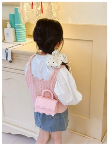 Close-up of pink mini crossbody bag with wavy edges and metal chain on a girl