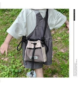 Detail of beige nylon crossbody bag with drawstring and mesh pocket on a child