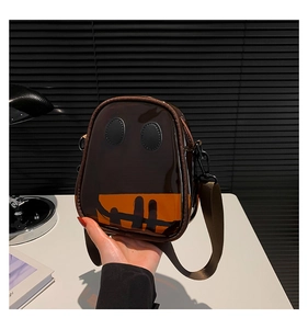 Detail of a brown transparent PVC crossbody bag with a ghost smile and wide nylon strap