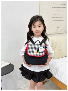 Detail of heart quilted kids backpack with checkered flap and plush puppy charm accessory