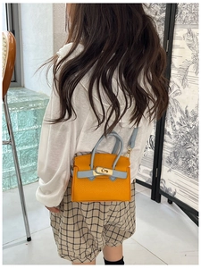 Detail of kids yellow mini bag with blue handles and golden metal rotating lock