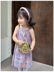 Detail of a shiny gold metallic bow handbag paired with a pink floral girl dress