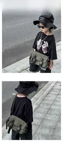 Outdoor street style view of army green nylon messenger bag for boys with buckles