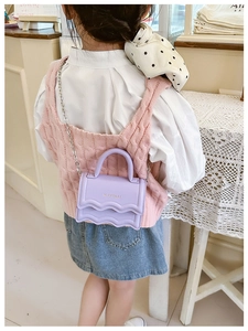 Detail of lavender mini crossbody bag with wavy flap and silver chain on child model