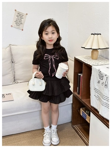 Dettaglio completo bambina nero con stampa fiocco rosa e gonna a pieghe a doppio strato