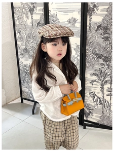 Detail of a mini orange and blue crossbody bag on a girl with checkered beret outfit