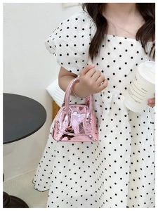 Détail d'un sac à main rose métallisé pour enfant avec poignées rondes et matelassage
