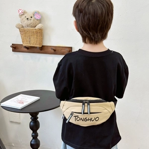Khaki canvas fanny pack for kids with adjustable strap and dual zippers on home background