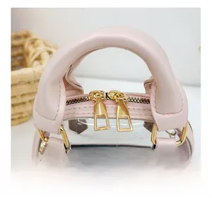 Detail view of smooth dual zipper closure and pink leather handle on transparent shell bag