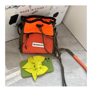 Detail of army green nylon crossbody bag with orange mesh pocket and drawstring closure