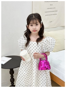 Détail du sac enfant en cuir verni matelassé rose rouge avec robe élégante à pois