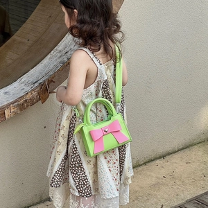 Vue détaillée du sac enfant vert avec grand nœud rose et ornement en forme de cœur
