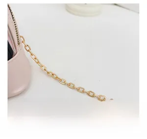 Detail of the golden metal chain strap on a pink leather shell-shaped crossbody bag