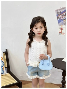 Dettaglio bambina con top a uncinetto bianco con frange e pantaloncini con borsa blu