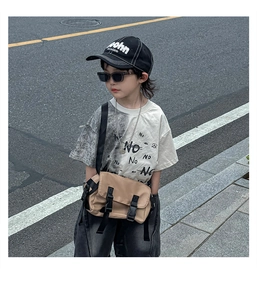 Close-up of khaki utility crossbody bag with black buckle on a child modeling outdoors