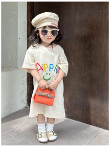 Detail of a beige girl's T-shirt with rainbow Apple text and a green smiley face graphic