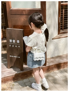 White wavy crossbody bag for girls with gold chain strap and metal logo in outdoor setting