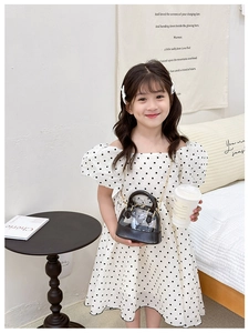 Girl's stylish polka dot dress paired with a mini black transparent chain crossbody bag