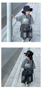 Detail of a black tactical crossbody bag paired with a gray street style boy's outfit