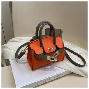 Detail of orange and grey pebbled leather bag with golden twist lock on white book