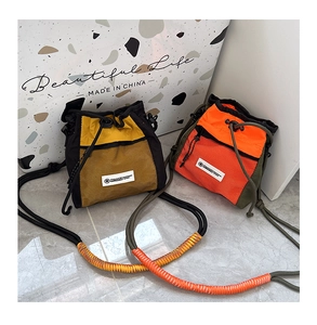 Detail of outdoor drawstring crossbody bag with mesh pocket and woven shoulder strap