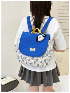 Detail of blue canvas school bag with floral pattern and cute puppy plush pendant