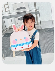 Detail of cute rabbit shell backpack with pink ears and bow held by child