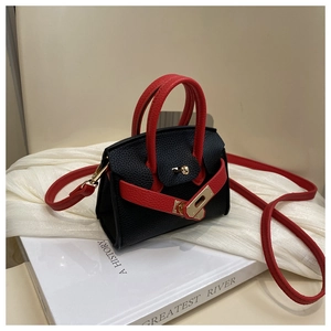 Detail of mini black pebbled leather tote with red straps and gold lock closure