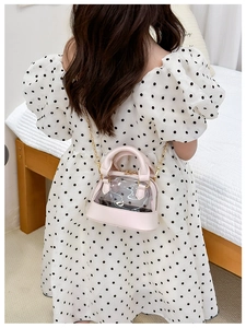 Detail of a pink transparent shell jelly crossbody bag worn by a girl in white dress