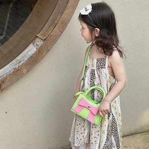 Détail du sac enfant avec nœud rose et cœur métallique sur similicuir vert fluo