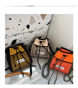 Detailed view of three kids' crossbody drawstring bucket bags with mesh pockets and contrast colors
