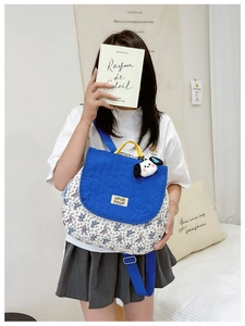 Detail of canvas backpack featuring quilted blue flap and cute dog plush pendant charm