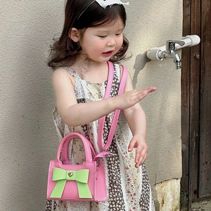Sac bandoulière rose pour fille avec nœud vert et boucle en cœur porté par un enfant