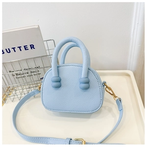 Dettaglio mini borsa azzurra con trama litchi, manico perlato e gancio dorato