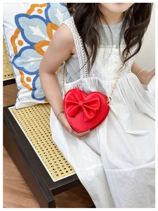 Fillette portant un sac cœur rouge avec nœud et bandoulière en chaîne dorée chic