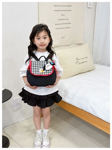 Close-up of heart-quilted black kids backpack with checkered flap and cute dog charm