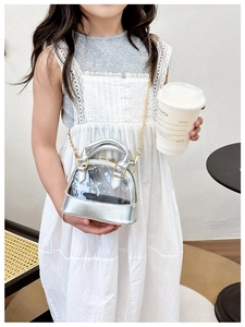 Detail of child wearing a silver shell-shaped jelly crossbody bag with gold chain strap