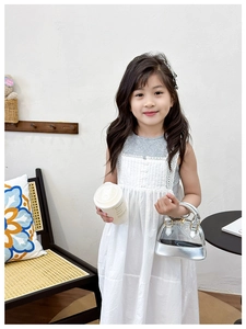 Detail of child model holding a silver and transparent shell jelly bag with lace dress