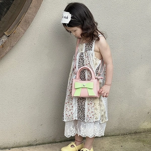 Fillette portant un sac bandoulière rose avec nœud vert et boucle cœur argent