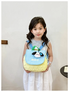 Close-up of quilted yellow kid backpack with blue plaid flap and cute puppy plush charm