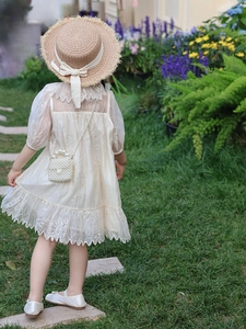 Détails tenue d'été fille avec robe brodée, chapeau de paille et mini sac en perles