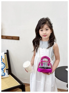 Detail of child wearing a rose red transparent shell bag with gold chain strap