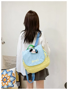 Quilted yellow shoulder bag with blue plaid flap and cute puppy charm on a model