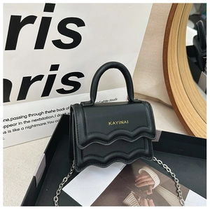 Detail of the black leather mini bag featuring wavy edge design and silver chain strap